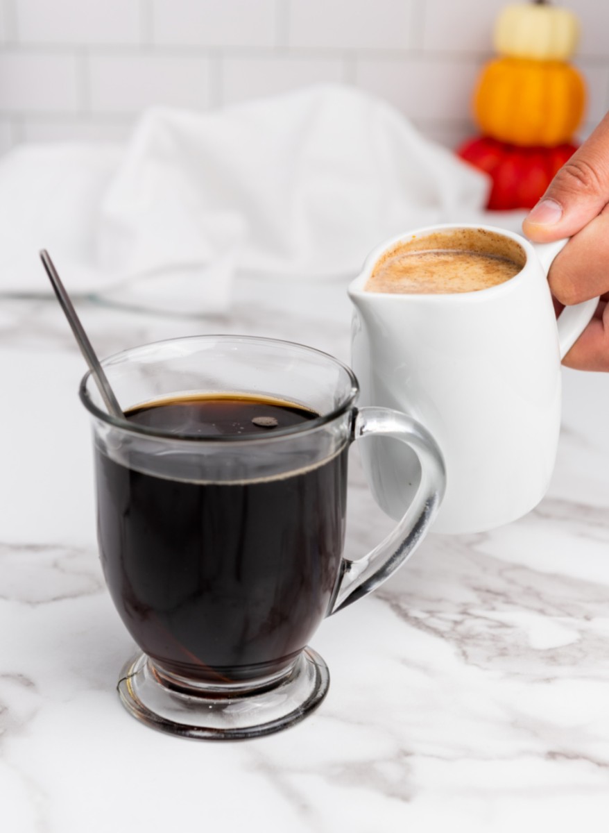 cup of coffee with container of pumpkin creamer