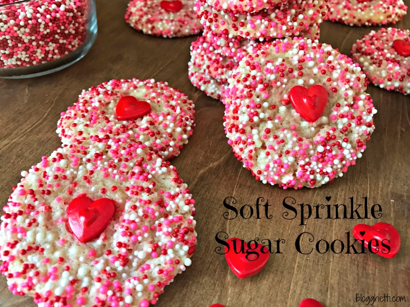 Surprise the Valentines in your life with these super Soft Sprinkle Sugar Cookies that are so easy to bake. No rolling or cutting out of the dough and super simple to decorate with the pink, red, and white sprinkles and a large red heart in the center of the cookie adds even more love to the baked goodness!