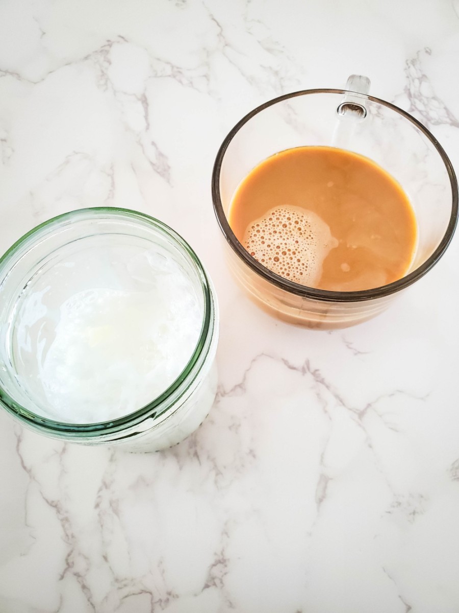 adding milk to latte in glass mug then topping with foam
