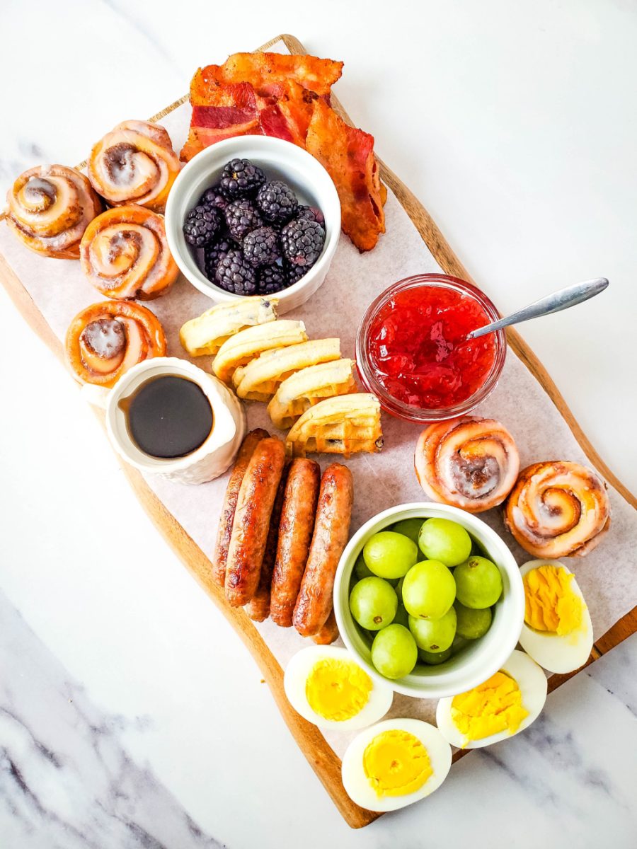 adding mini cinnamon rolls and bacon to charcuterie board